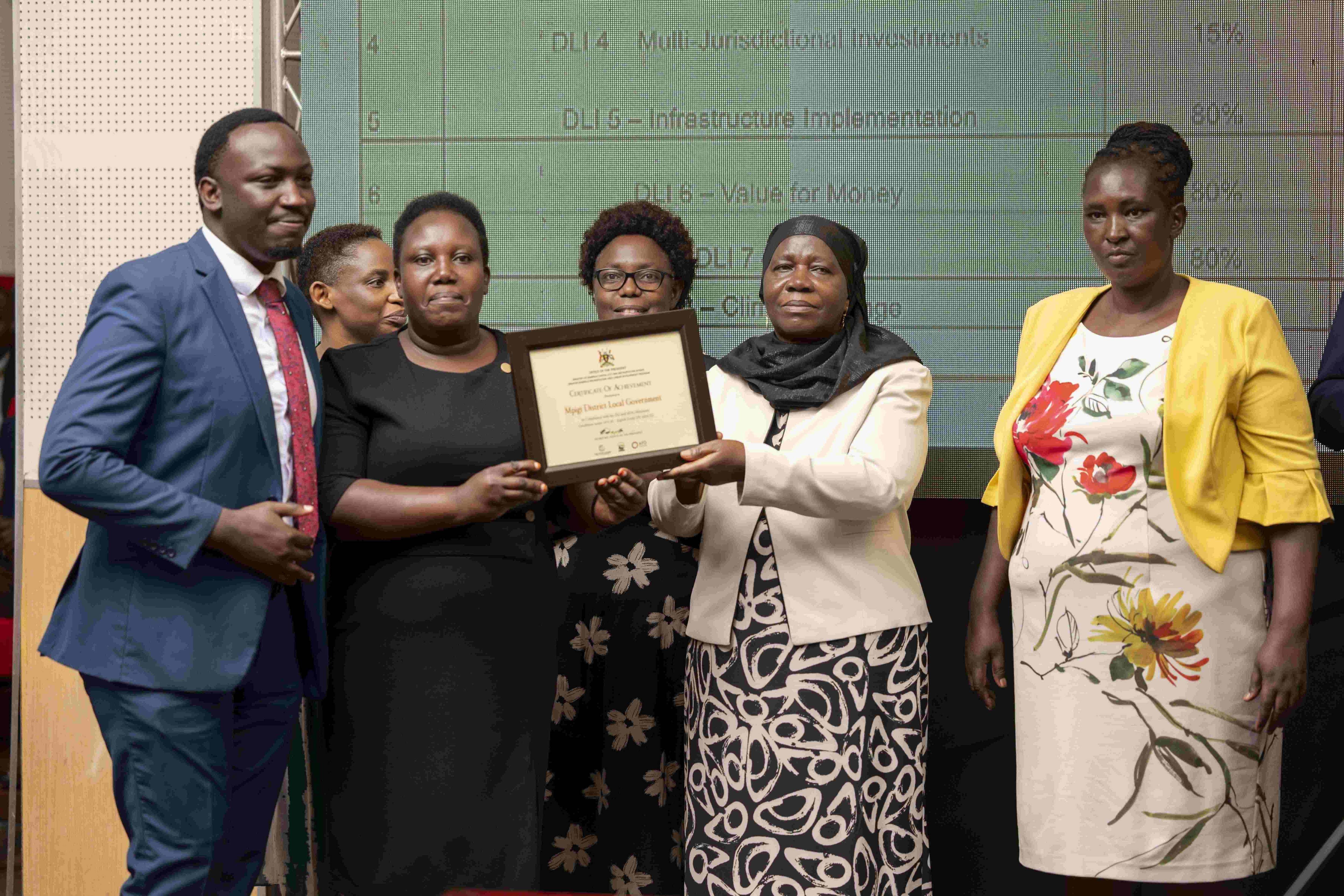 Hon. Minsa Kabanda - Minister for Kampala Capital City and Metropolitan Affairs recognizes Mpigi DLG for excellence during APA III launch at MoFPED Headquarters